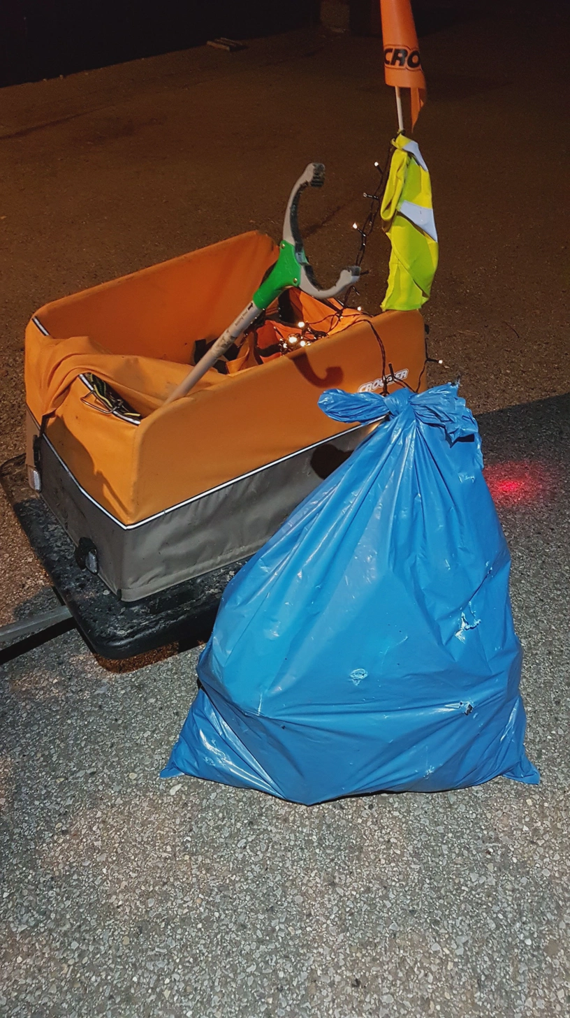 Gefüllter Müllsack steht vor einem Fahrradanhänger.
