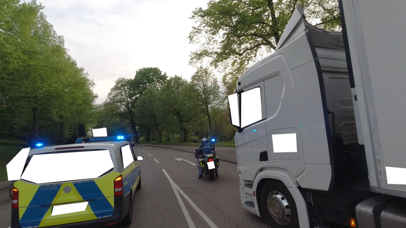 Von der Kamera eines Radfahrers. Auf dem Fahrstreifen rechts steht der Lkw, etwas davor ein Motorrad mit Polizist drauf und blaulicht, auf dem Fahrstreifen vor dem Radfahrer ein Polizeiauto mit Blaulicht.