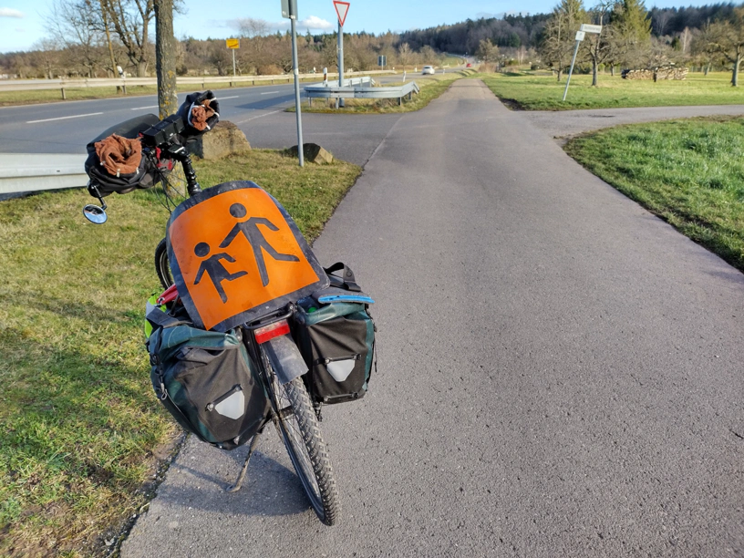 Fahrrad auf einem Feldweg und mit einem &lsquo;Vorsicht Kinder&rsquo; Schild auf dem Gepäckträger