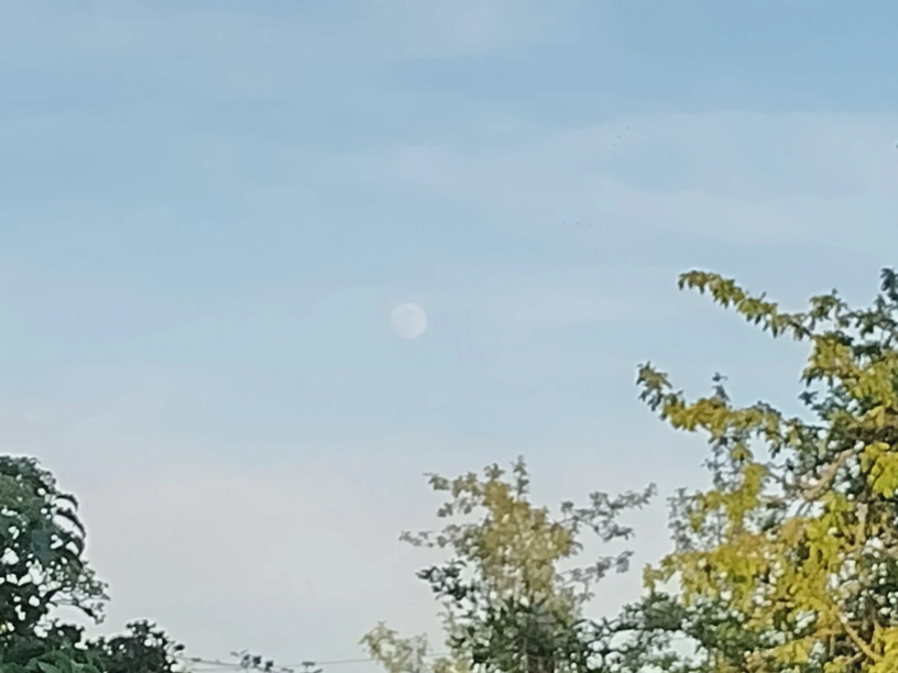Reingezoomtes Foto und relativ klein zu erkennen der Mond am Himmel.