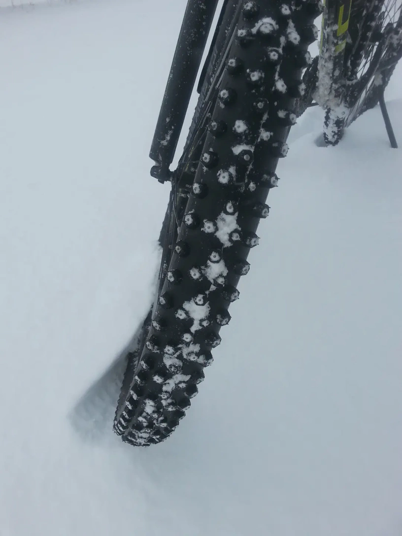 Winterreifen am Fahrrad im Schnee. Deutlich sind die Spikes in jedem einzelnen Stollen sichtbar.