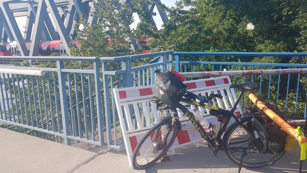Mein Fahrrad auf der BrÃ¼cke in Karlsruhe, die Ã¼ber den Rhein fÃ¼hrt. Das Fahrrad steht vor dem BrÃ¼ckengelÃ¤nder, dahinter eine ZugbrÃ¼cke mit einem gerade darauf fahrenden Zug.